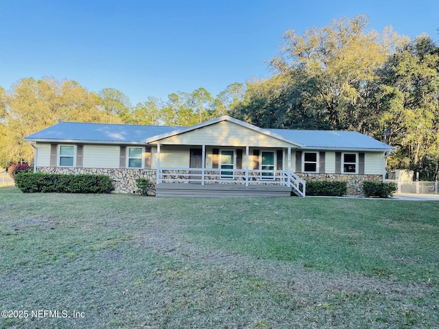 single story home featuring stone siding, covered porch, metal roof, and a front lawn