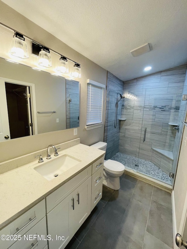 full bath featuring a stall shower, a textured ceiling, toilet, and vanity