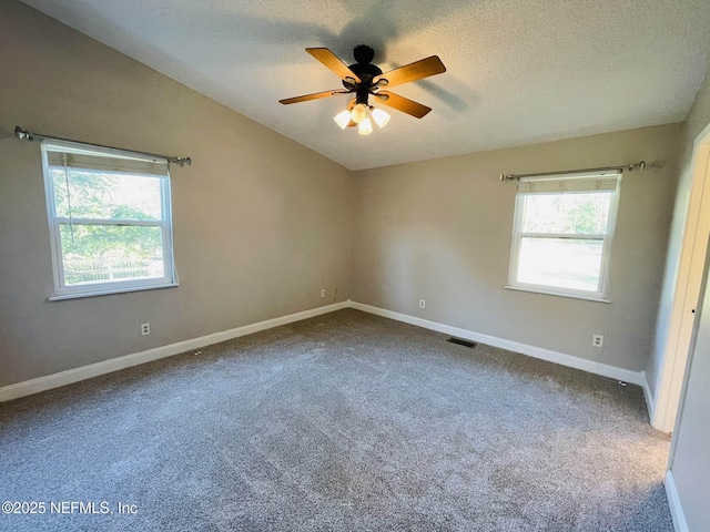 empty room with carpet floors, lofted ceiling, visible vents, a textured ceiling, and baseboards