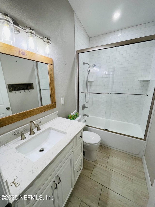 full bath with enclosed tub / shower combo, a textured wall, toilet, and vanity