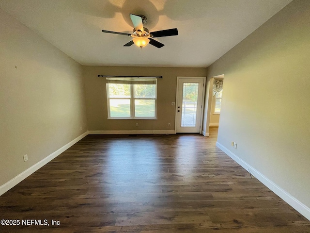 spare room with vaulted ceiling, dark wood-style flooring, and baseboards