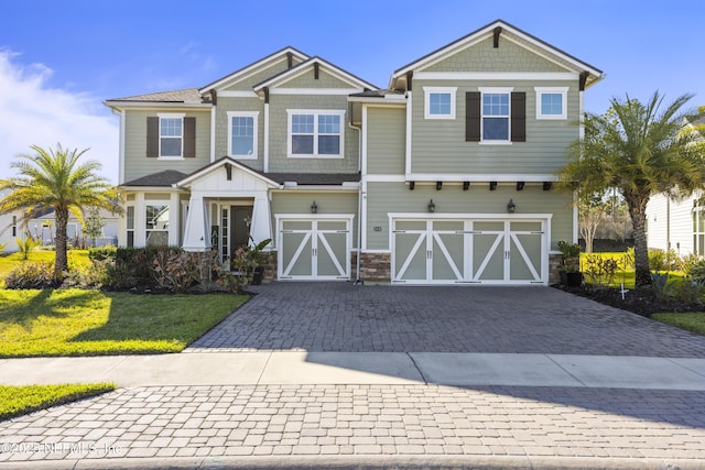 craftsman-style house featuring a front yard, decorative driveway, and a garage