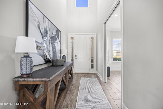 foyer entrance with light wood-style flooring, baseboards, and ornamental molding