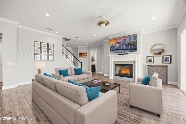 living room featuring light wood finished floors, stairway, crown molding, and baseboards