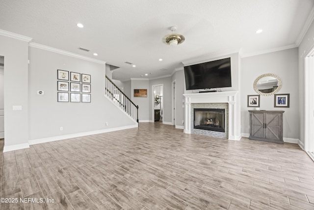 unfurnished living room featuring stairway, visible vents, baseboards, ornamental molding, and light wood-type flooring