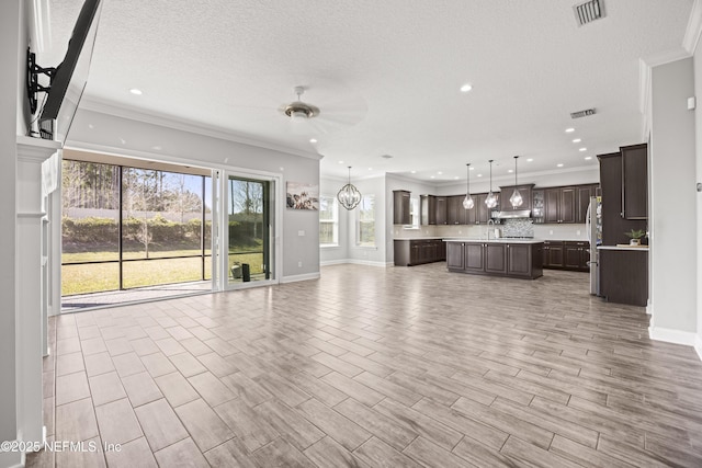 unfurnished living room with wood finish floors, visible vents, a ceiling fan, and crown molding