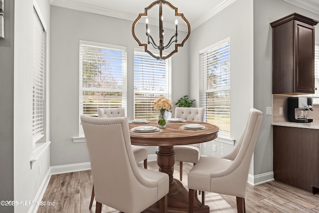 dining room with a chandelier, light wood finished floors, and crown molding