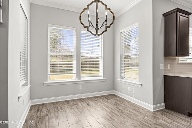 unfurnished dining area featuring an inviting chandelier, light wood-style flooring, plenty of natural light, and ornamental molding