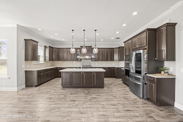 kitchen featuring dark brown cabinets, appliances with stainless steel finishes, a center island, and light countertops