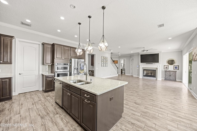 kitchen with dark brown cabinets, a fireplace, stainless steel appliances, and a sink