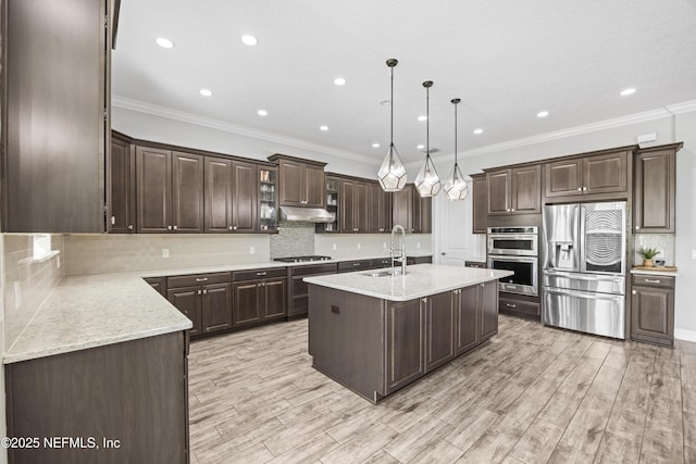 kitchen featuring an island with sink, a sink, dark brown cabinets, under cabinet range hood, and appliances with stainless steel finishes