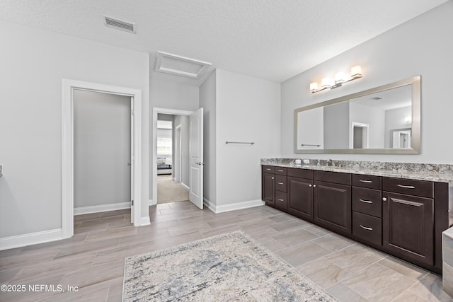 bathroom with visible vents, a textured ceiling, vanity, and baseboards