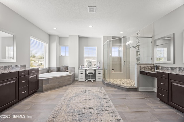 full bathroom featuring vanity, a garden tub, a stall shower, and a textured ceiling