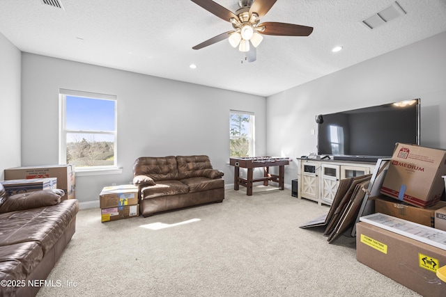 living room with a ceiling fan, light colored carpet, visible vents, and baseboards