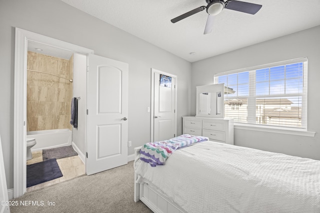 bedroom with baseboards, light colored carpet, ensuite bathroom, a textured ceiling, and a ceiling fan