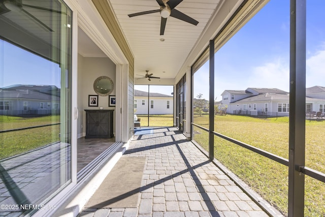 unfurnished sunroom with a residential view and ceiling fan