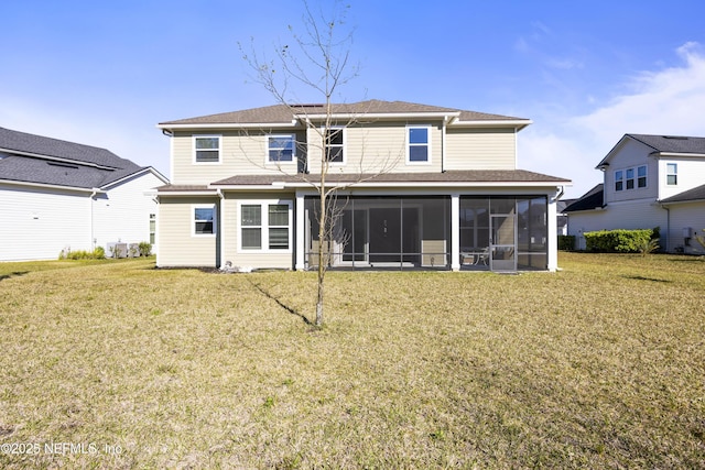 back of property with a lawn, a sunroom, and roof with shingles