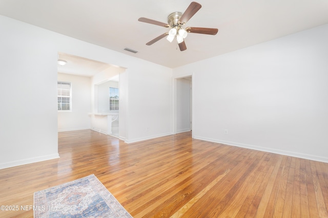 empty room with a ceiling fan, visible vents, light wood-style flooring, and baseboards