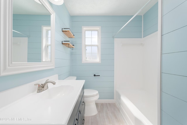 full bath featuring shower / bath combination, toilet, wood finished floors, a textured ceiling, and vanity