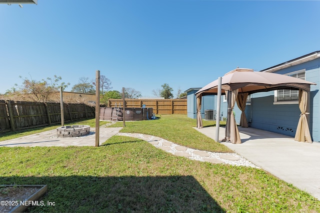 view of yard featuring central AC unit, an outdoor fire pit, a fenced backyard, a gazebo, and a patio area