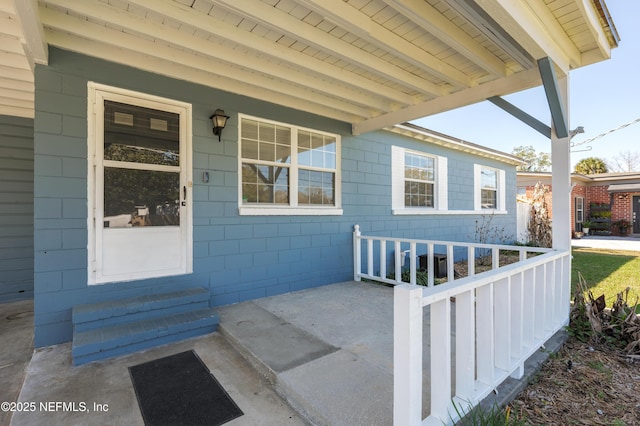 view of exterior entry featuring covered porch and concrete block siding