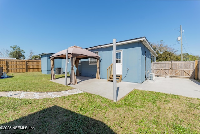 rear view of house with entry steps, a lawn, a patio, a fenced backyard, and a gate