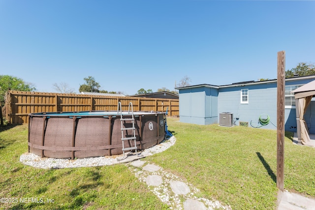 view of yard with a fenced in pool, fence, and central air condition unit