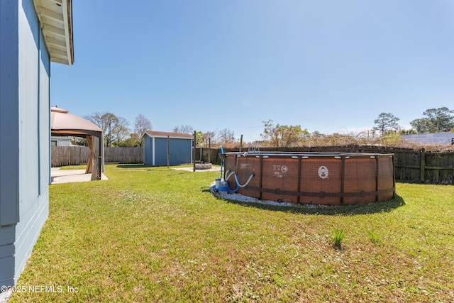 view of yard with a fenced in pool, a storage unit, a gazebo, a fenced backyard, and an outdoor structure