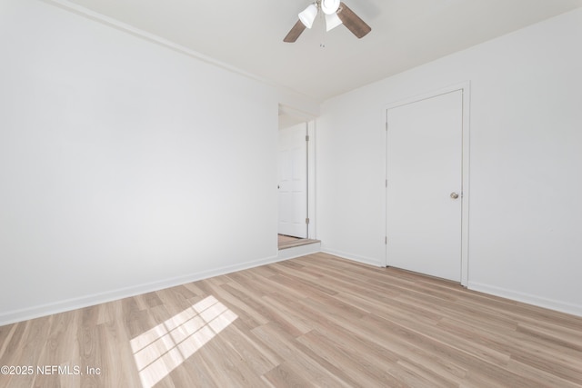 empty room featuring baseboards, a ceiling fan, and light wood-style floors