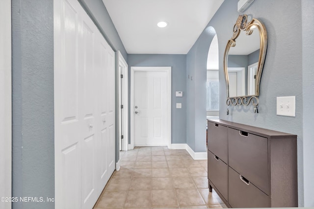 corridor featuring light tile patterned floors and baseboards