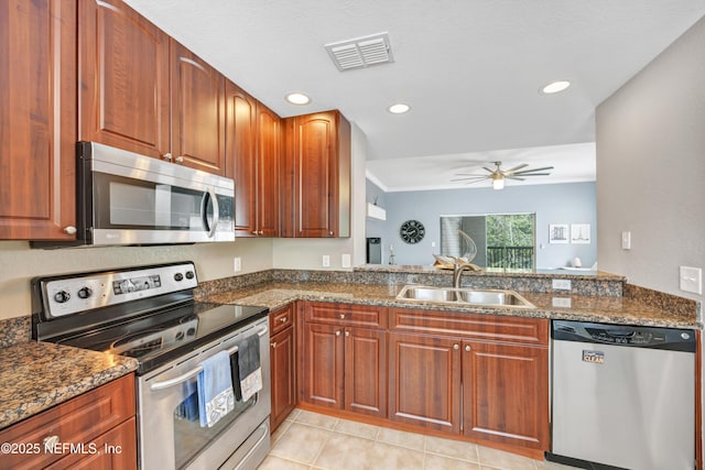 kitchen with a sink, visible vents, a ceiling fan, appliances with stainless steel finishes, and dark stone countertops