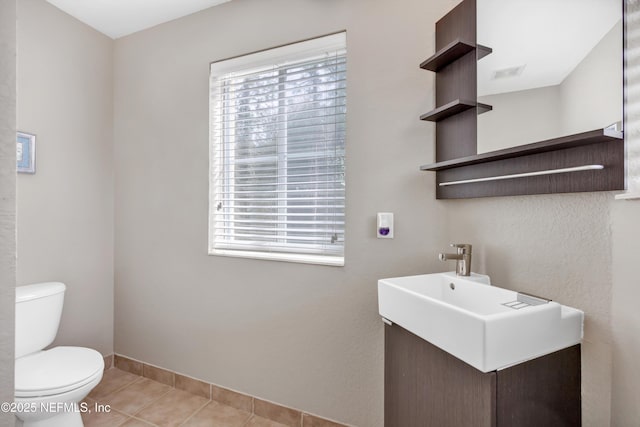 half bathroom featuring a healthy amount of sunlight, vanity, toilet, and tile patterned floors