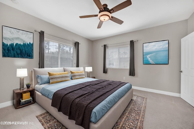 bedroom with a ceiling fan, light colored carpet, multiple windows, and baseboards