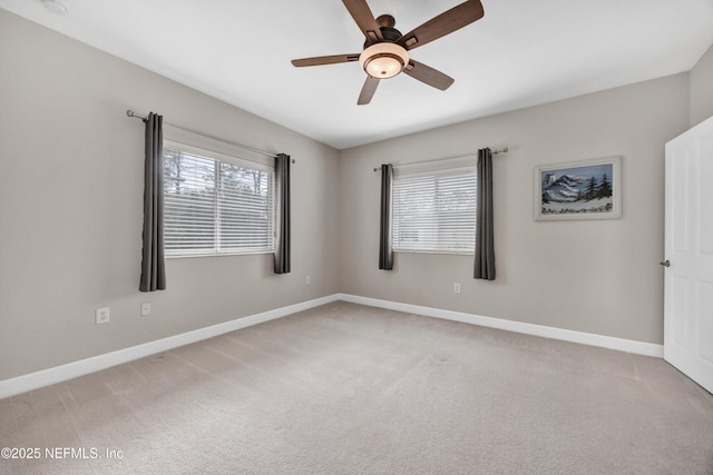 carpeted spare room with baseboards, a ceiling fan, and a healthy amount of sunlight