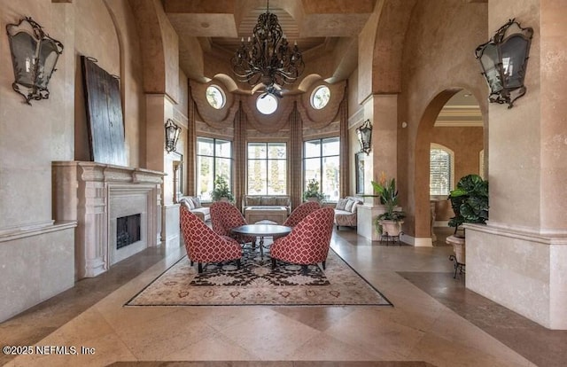 dining space featuring arched walkways, a fireplace, a notable chandelier, a high ceiling, and coffered ceiling