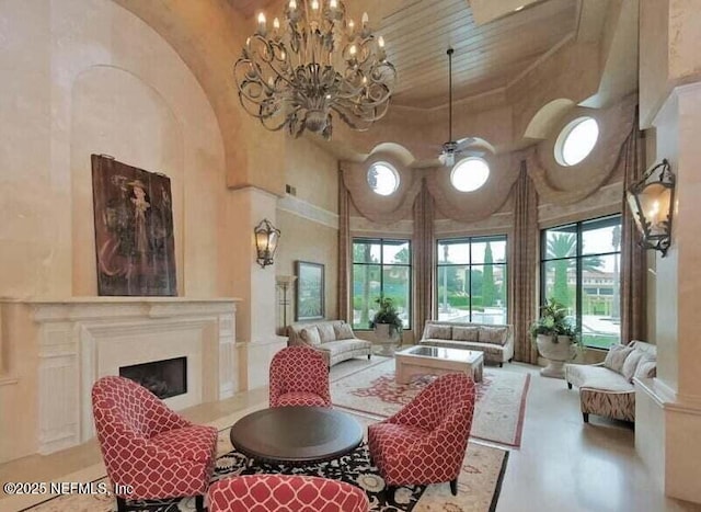 interior space featuring a fireplace, a high ceiling, and ceiling fan with notable chandelier