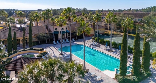 community pool with an in ground hot tub, a patio area, and a residential view