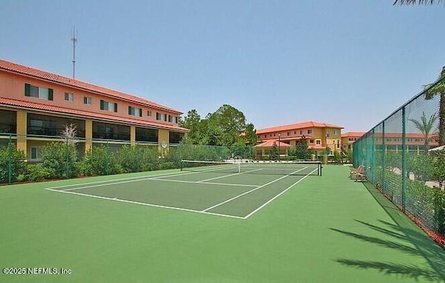 view of tennis court with community basketball court and fence