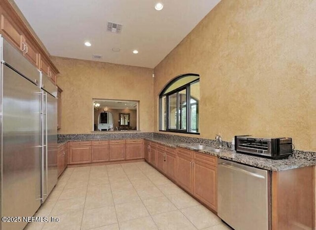 kitchen with stainless steel appliances, recessed lighting, visible vents, a sink, and dark stone countertops