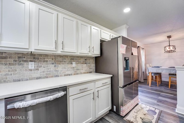 kitchen featuring decorative light fixtures, stainless steel appliances, light countertops, light wood-style flooring, and white cabinets