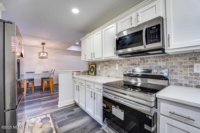 kitchen with wood finished floors, white cabinets, light countertops, appliances with stainless steel finishes, and backsplash