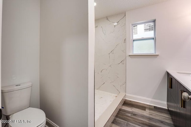 full bath featuring wood finished floors, a marble finish shower, toilet, and baseboards