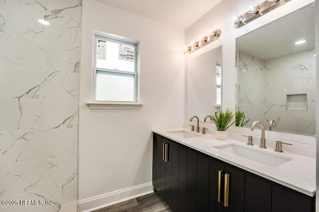 full bathroom with double vanity, a sink, a textured ceiling, and wood finished floors