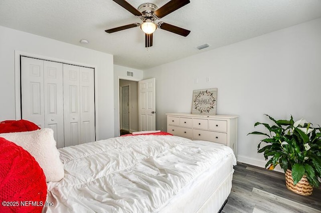 bedroom with a closet, wood finished floors, visible vents, and a ceiling fan