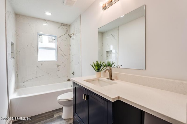 bathroom featuring visible vents, shower / bathing tub combination, toilet, vanity, and wood finished floors