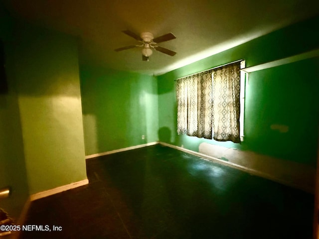 empty room with ceiling fan and baseboards