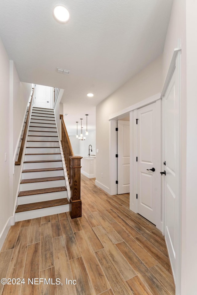 staircase featuring visible vents, baseboards, wood finished floors, and recessed lighting