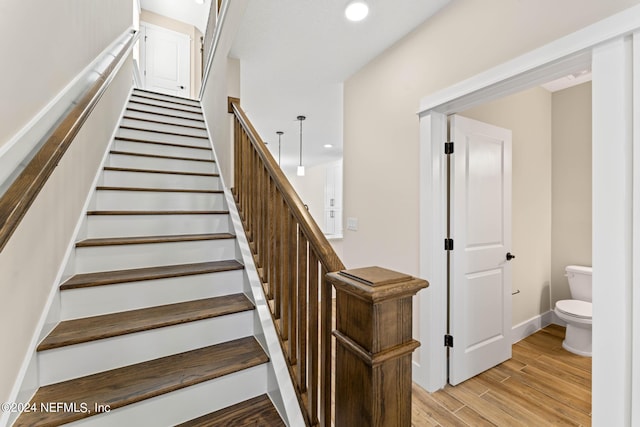 stairway with baseboards, wood finished floors, and recessed lighting