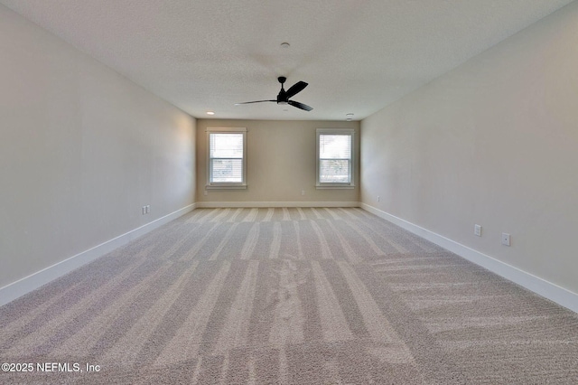 spare room featuring light carpet, a ceiling fan, baseboards, and a textured ceiling