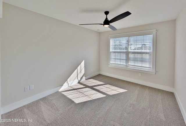 carpeted spare room featuring baseboards and a ceiling fan